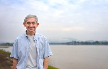 Asyalı son sınıf öğrencisi Mekong Nehri 'nin yanında duruyor. Yetişkin erkek gezgin Altın Üçgen, Chiang Rai, Tayland. Yaşlılar yaşam tarzı, tatil, seyahat.