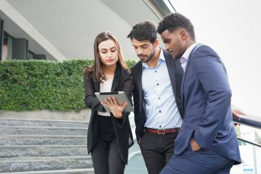multiracial business colleagues using digital tablet talking or discussing work together outside building,concept business people lifestyle,working,friendship                                 