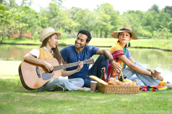 young diversity genders friends,man,woman and woman transgender enjoy leisure time in the park,having picnic,playing music take pleasure in nature,concept of people lifestyle,friendship,holiday,relaxing