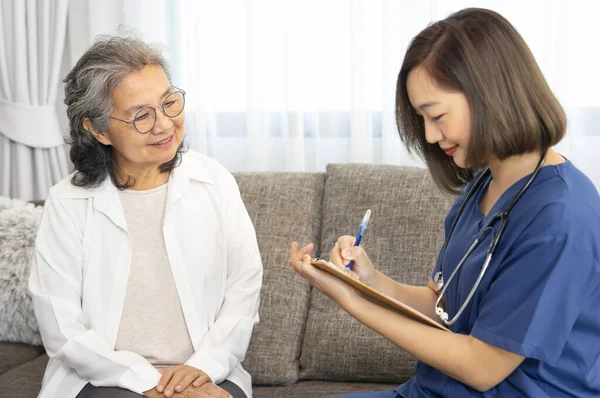 A senior woman giving a health interview to a home visiting nurse, a young female taking a patient data notes on flip chart paper,concept of elderly health,homecare,home health nursing