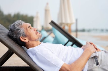 Gri saçlı ve sakallı sakin bir adam yaz mevsiminde plaj sandalyesinde uyuyor yaşlı yetişkin bir erkek doğada dinleniyor, yaşlılar için yaşam tarzı, tatil, seyahat, refah...