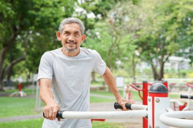 Sağlıklı bir portre. Son sınıf öğrencisi, spor aletleriyle spor yapıyor. Olgun bir adam parkta spor yapıyor.                                  