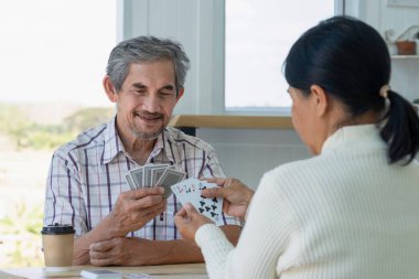 happy senior couple enjoy playing cards game together, concept elderly pensioner lifestyle, entertainment, recreation, encourages social interaction, help memory retention 