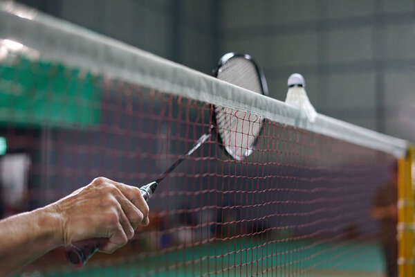 Мужчина держит ракетку ударил шаттл в сети, бадминтон игрок, турнир, тренировки     