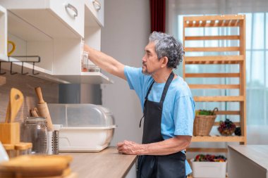 Mutfakta çalışan meşgul bir son sınıf öğrencisi, yaşlılar, ev hayatı, yemek pişirme