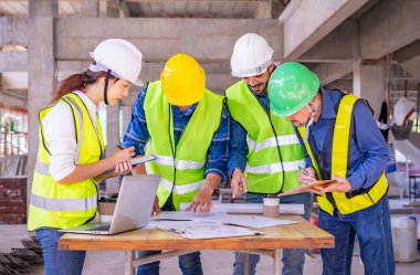 İnşaat şantiyesinin teftiş yapısından önce masada mühendislik ekibi toplantısı var. İnşaat mühendisleri inşaat halinde.