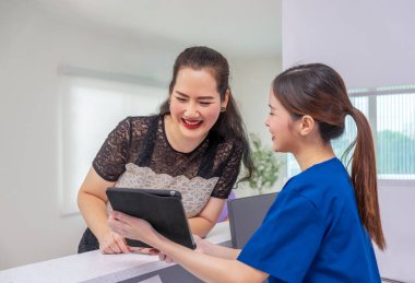 Gülümseyen bir portre doktoru, bir hemşireye güzellik kliniğindeki bir müşteriyi tedavi etmesi için tarif ederken,