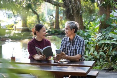 Asyalı son sınıf evli çift hobilerini internette akıllı telefonlar okuyarak ve sörf yaparak geçiriyor.