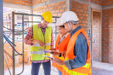 Genç bir Asyalı elektrikçi elektrik tesisat sistemini saha çalışması yaparken deneyimli emlak ev projeleri müfettişine anlatıyor. 