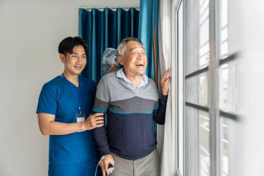Bakıcı ya da hemşire yardımcısı iyileşen yaşlı bir hastaya yardım eder. Pencere kenarında bastonla yürür, doğaya bakar, yaşlılara bakar, akıl sağlığı, zihinsel destek...