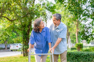 Asyalı kıdemli adam bahçede yürüyüş, aile yaşam tarzı, sağlık ve rehabilitasyon yaparken karısına bakıyor.