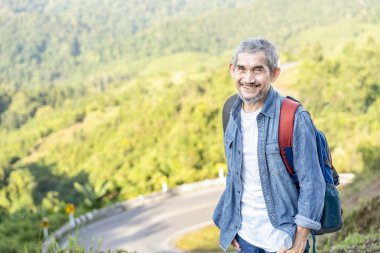 Sırt çantasıyla gezen, yol kenarında duran, yaşlı gezgin, maceracı Asyalı son sınıf öğrencisi.