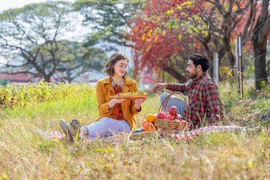 Kafkas ailesi sonbahar parkında piknik yapıyor. Genç romantik çift, sonbahar hasadını birlikte harika bir çayırda kutluyor.
