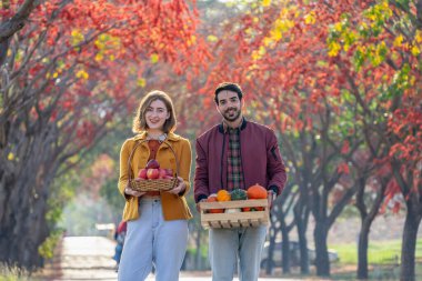 Sepet ve meyve sandığı taşıyan genç beyaz bir çift portresi, aile yaşam tarzı konsepti, sonbaharda hasat mevsimi
