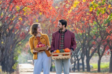 Sepet ve meyve sandığı taşıyan genç beyaz bir çift portresi, aile yaşam tarzı konsepti, sonbaharda hasat mevsimi