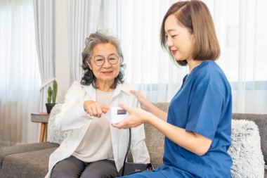 Ziyaretçi hemşire evde yaşlı kadına bakıyor, hayati belirtileri, tansiyonu ölçüyor, sonucu bildiriyor ve tavsiyelerde bulunuyor, yaşlı sağlık hizmetleri kavramı, ev sağlık hizmetleri, sağlık sigortası