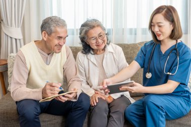 Ziyaretçi hemşireler tablet bilgisayar kullanırken, Asyalı üst düzey çiftlere kişisel sağlık hizmetleri için tavsiye verirken, yaşlı erkekler de yaşlı sağlık hizmetleri, sağlık sigortası, ev sağlığı hizmetleri gibi konuları not alıyorlar.