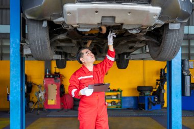 Asya 'nın kıdemli tamirci işletme sahibi. Garaj hizmetinde kaldırılan aracı kontrol ediyor.