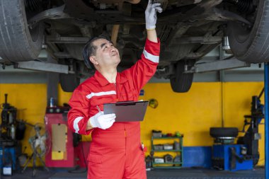 Asya 'nın kıdemli tamirci işletme sahibi. Garaj hizmetinde kaldırılan aracı kontrol ediyor.