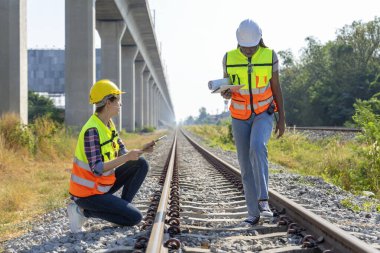 Genç çok ırklı kadın demiryolu mühendisi, Kafkas ve Afrikalı, demiryolu raylarını teftiş, tren konsepti, tren, demiryolu altyapısı standart teftiş ve bakım  