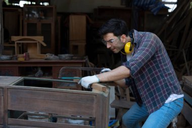 Genç marangoz portresi dükkanında çalışıyor, zanaatkar ahşap döşeme ve onarım işleriyle uğraşıyor. 