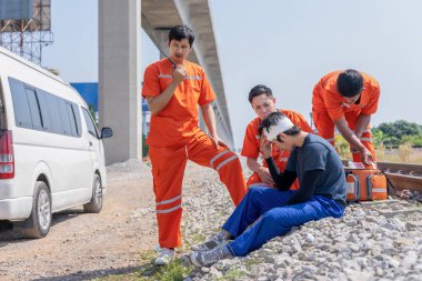 İlk yardım ekibi, acil durum kazasında yaralanan hastaya yardım ediyor. Tren raylarında ve telsizle hastaneye sevk ediliyor.