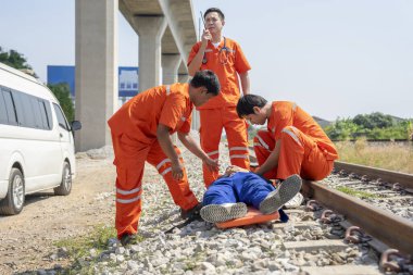 İlk yardım ekibi, acil durum kazasında yaralanan hastaya yardım ediyor. Tren raylarında ve telsizle hastaneye sevk ediliyor.