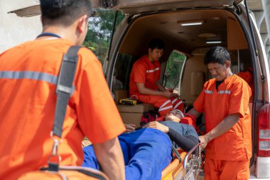 İlk yardım ekibi, acil durum kazasında yaralanan hastayı sedyeye yatırıp hastaneye naklediyor.
