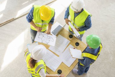 İnşaat şantiyesinin teftiş yapısından önce masada mühendislik ekibi toplantısı var. İnşaat mühendisleri inşaat halinde.