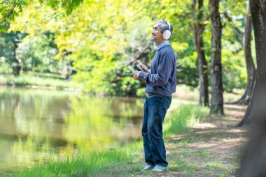 Gri saçlı son sınıf öğrencisi kulaklık takıyor ve elinde akıllı bir telefon tutuyor. Müzik dinleyip dans ettiği anda mutlu oluyor. 