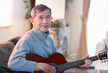 Evde gitar çalarken üst düzey bir adamın portresi, yaşlılar için yaşam tarzı, etkinlik, hobi, eğlence