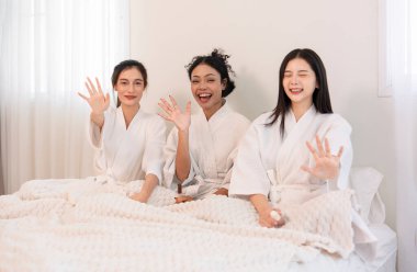 Bornozlu genç, çok ırklı arkadaşların portresi. Yatakta oturup, birlikte kutluyor, eğleniyor, gülüyor ve spa odasında dinleniyorlar.