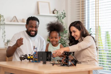 Aile, çocukların BTMM deneğinde robot devresi ve elektronik kablo öğrenmesine yardım ederken eğleniyor. 