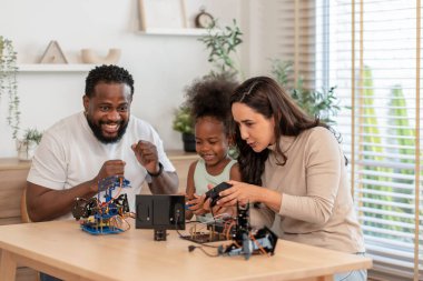 Aile eğleniyor, ebeveynler çocuğa robot devresi öğrenmesinde yardım ediyor, BTMM dersinde elektronik kablo, konsept aile yaşam tarzı, yetişkin yardım çocuğu, evde eğitim