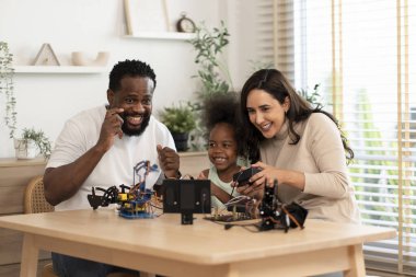 Aile eğleniyor, ebeveynler çocuğa robot devresi öğrenmesinde yardım ediyor, BTMM dersinde elektronik kablo, konsept aile yaşam tarzı, yetişkin yardım çocuğu, evde eğitim