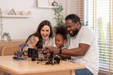 Aile eğleniyor, ebeveynler çocuğa robot devresi öğrenmesinde yardım ediyor, BTMM dersinde elektronik kablo, konsept aile yaşam tarzı, yetişkin yardım çocuğu, evde eğitim
