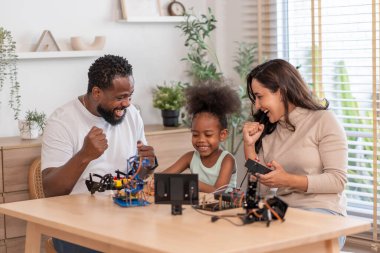 Aile eğleniyor, ebeveynler çocuğa robot devresi öğrenmesinde yardım ediyor, BTMM dersinde elektronik kablo, konsept aile yaşam tarzı, yetişkin yardım çocuğu, evde eğitim