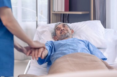 Üniformalı bir hemşireye bakan, onu destekleyen, el ele tutuşan ve cesaretlendiren yaşlı erkek hasta sahnesi.
