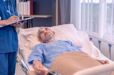 Hastanedeki hasta yatağında yatarken hemşire mülakatına sağlık verileri veren yaşlı bir adamın olay yeri. 