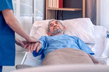 Üniformalı bir hemşireye bakan, onu destekleyen, el ele tutuşan ve cesaretlendiren yaşlı erkek hasta sahnesi.