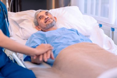 Üniformalı bir hemşireye bakan, onu destekleyen, el ele tutuşan ve cesaretlendiren yaşlı erkek hasta sahnesi.