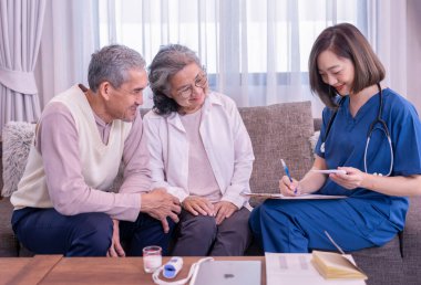 Yaşlı çift, evde civa ölçen ve tavsiyelerde bulunan ziyaretçi bir hemşireye konsantre olur. Yaşlılar için sağlık hizmeti kavramı, ev bakımı.