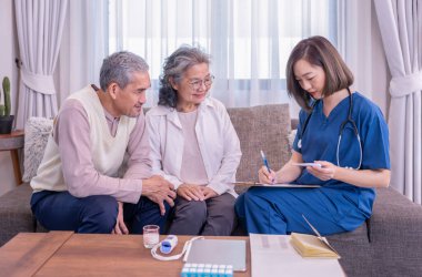 Yaşlı çift, evde civa ölçen ve tavsiyelerde bulunan ziyaretçi bir hemşireye konsantre olur. Yaşlılar için sağlık hizmeti kavramı, ev bakımı.