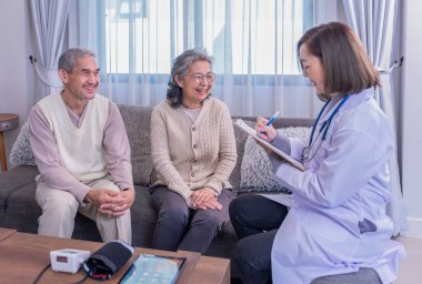 Kıdemli çift üniformalı doktorla konuşuyor. Evrak işleri, yaşlı sağlık hizmetleri, ev bakımı, sağlık sigortası hakkında danışmanlık yapıyor, inceleme yapıyor, bilgi topluyor.