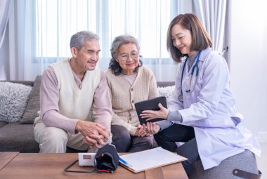 Genç bayan profesyonel doktor odada tablet bilgisayar kullanan Asyalı yaşlı çifte danışmanlık yapıyor.