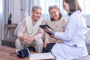 Genç bayan profesyonel doktor odada tablet bilgisayar kullanan yaşlı çiftlere danışmanlık yapıyor, yaşlı çiftlere özen gösteriyorlar.