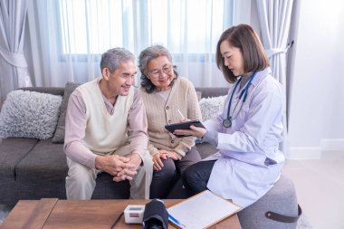 Genç bayan profesyonel doktor odada tablet bilgisayar kullanan Asyalı yaşlı çifte danışmanlık yapıyor.