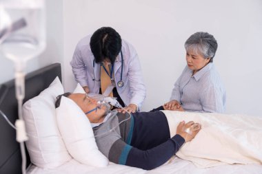 Hüzünlü yaşlı bir kadının ölüm döşeğinde, serum ve oksijenle el ele tutuşması, bir doktorun fiziksel muayene, konsept palyatif bakım, yaşam bakımı,