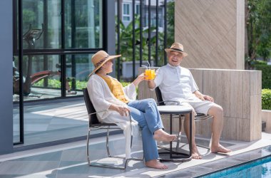 Mutlu yaşlı çift masada taze içeceklerle konuşmaktan, oturmaktan, havuz başında dinlenmekten, yaşlılar tatil beldesi olan tropikal tatil beldesini ve kaplıcaları gezmekten hoşlanır.