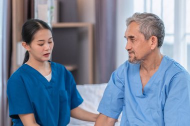 Hasta semptomlarını gözlemlemek için sağlık kontrolü yapılırken bir hemşireyle konuşan kıdemli bir hastanın portresi.